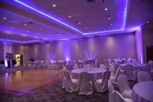 A room with purple lighting and white chairs