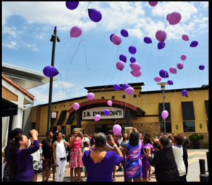 A group of people standing outside with balloons.