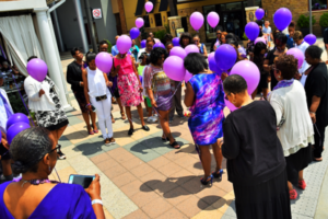 A group of people standing around each other holding balloons.