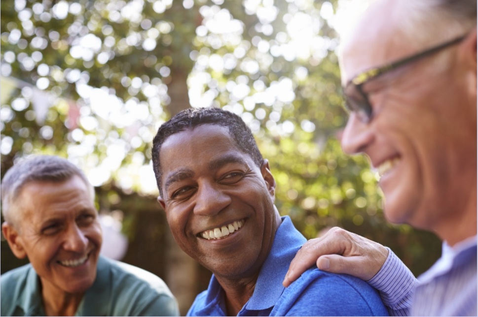 Three men smiling and laughing together outside.